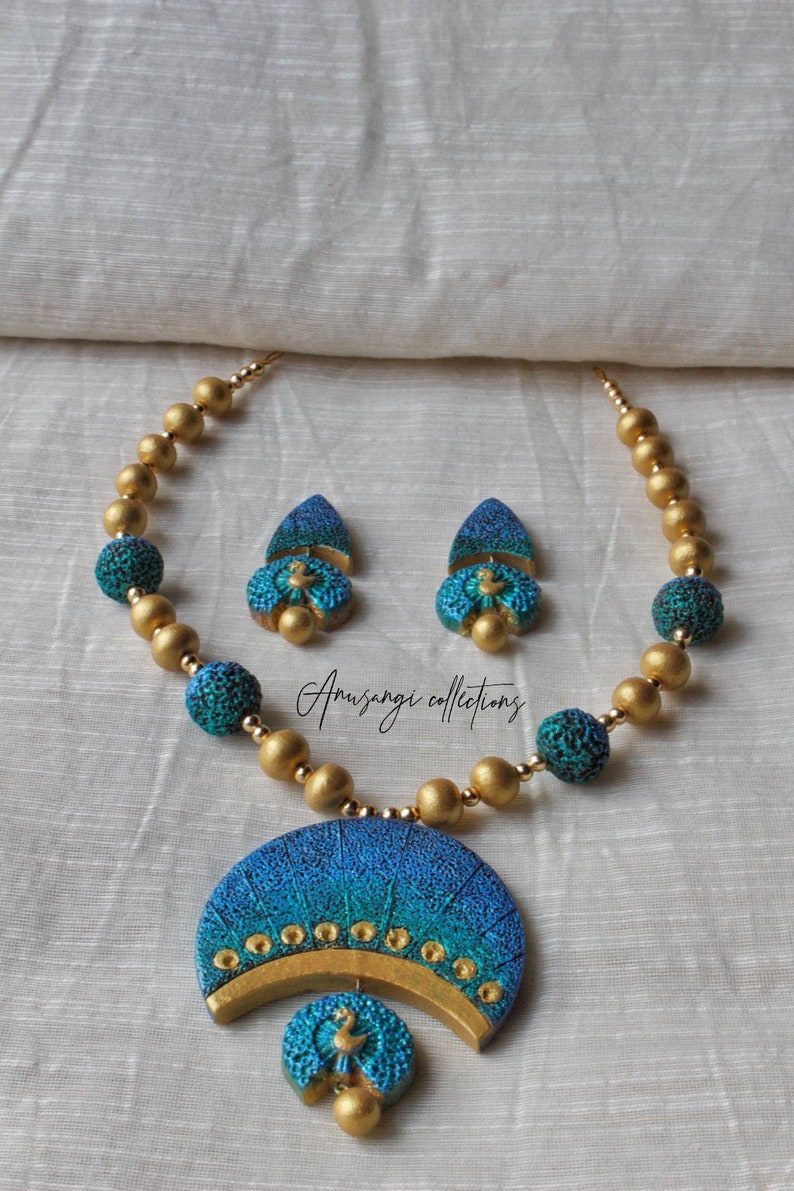 Experience elegance and charm with the Nelamangala Mayura Terracotta Jewelry set. This intricately handcrafted necklace features a stunning peacock design and is accompanied by a lovely pair of earrings.