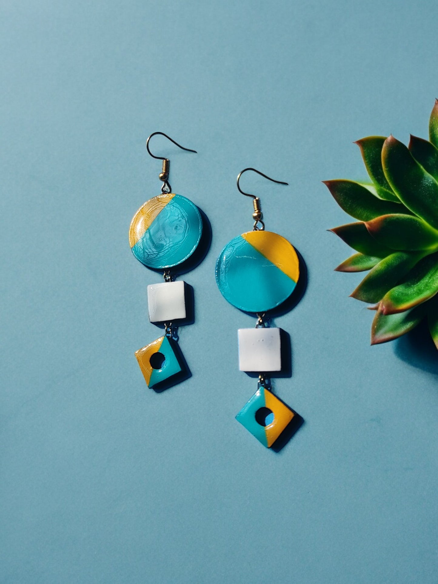 Skillfully handcrafted from terracotta, these earrings showcase a stunning color combination of yellow and teal.