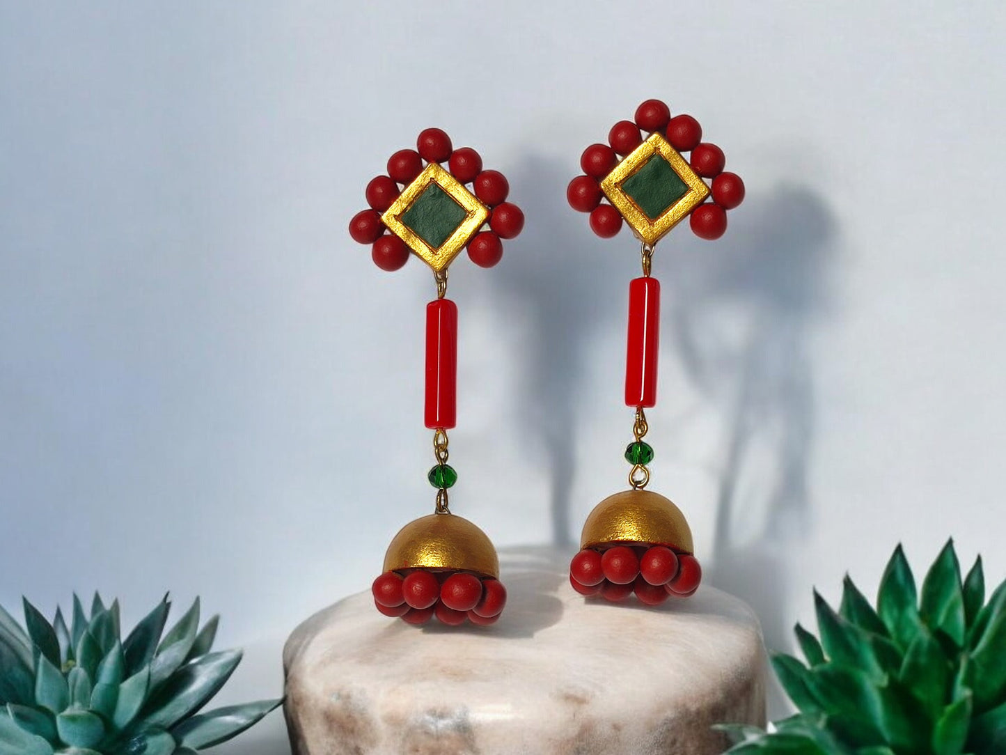 Experience exquisite adornment with our Abha Long Terracotta Jhumka. Each piece boasts elaborate patterns in a vibrant red, green, and gold color scheme, exuding a sense of opulence and exclusivity. Enhance your fashion with this essential statement accessory.

