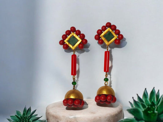 Experience exquisite adornment with our Abha Long Terracotta Jhumka. Each piece boasts elaborate patterns in a vibrant red, green, and gold color scheme, exuding a sense of opulence and exclusivity. Enhance your fashion with this essential statement accessory.