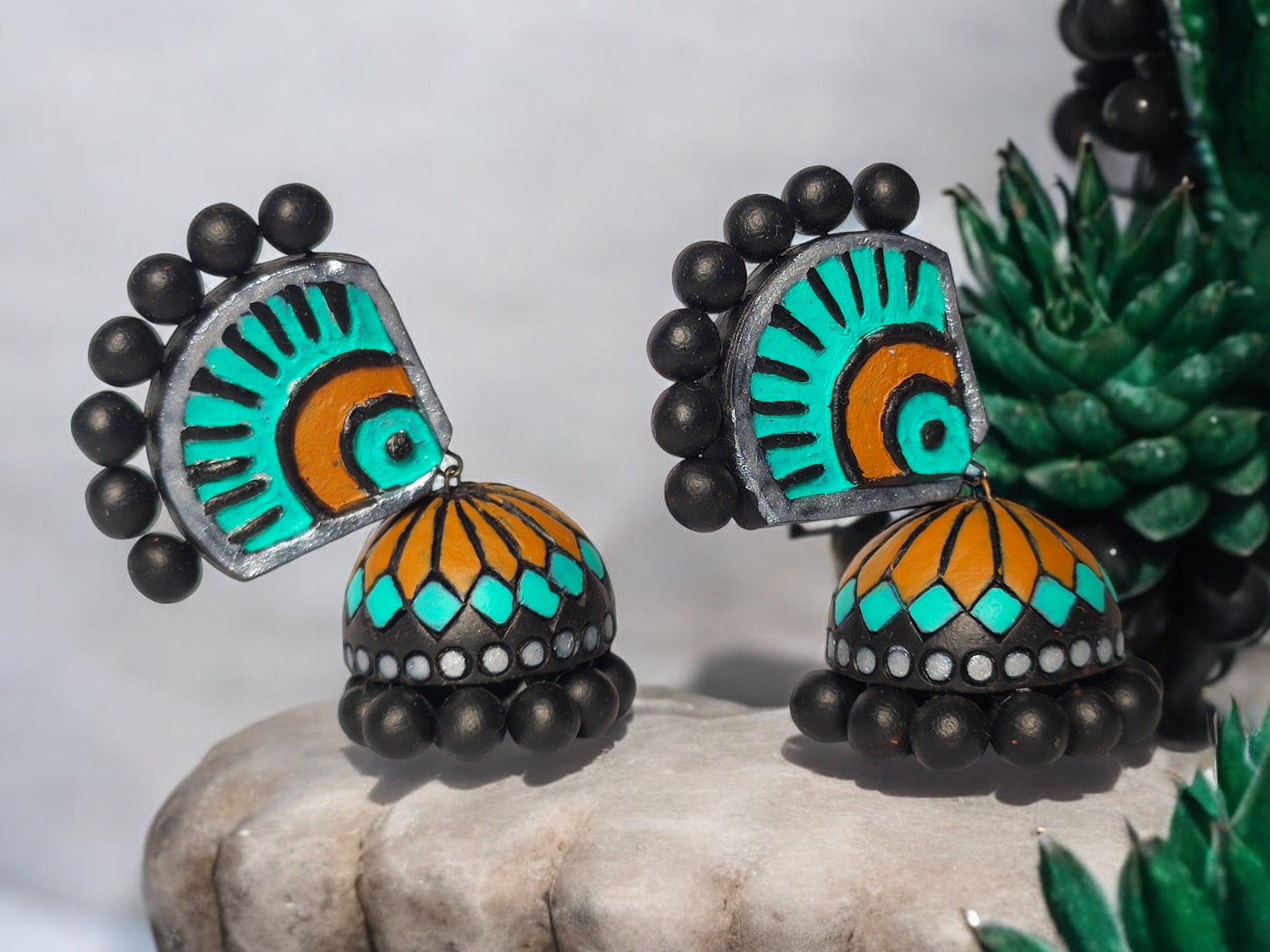 Experience the luxury of the Aachal Terracotta Jhumka, adorned with a captivating blend of teal blue, mustard yellow, and bold black. These handcrafted jhumkas, made from premium terracotta, add a touch of sophistication and elegance to any outfit, making it an exclusive must-have accessory.

