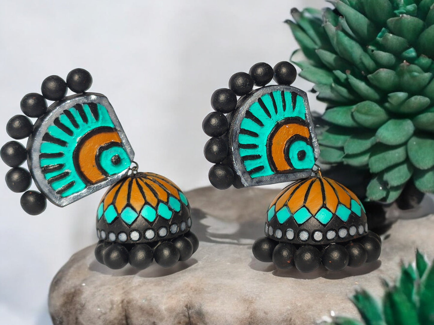 Experience the luxury of the Aachal Terracotta Jhumka, adorned with a captivating blend of teal blue, mustard yellow, and bold black. These handcrafted jhumkas, made from premium terracotta, add a touch of sophistication and elegance to any outfit, making it an exclusive must-have accessory.

