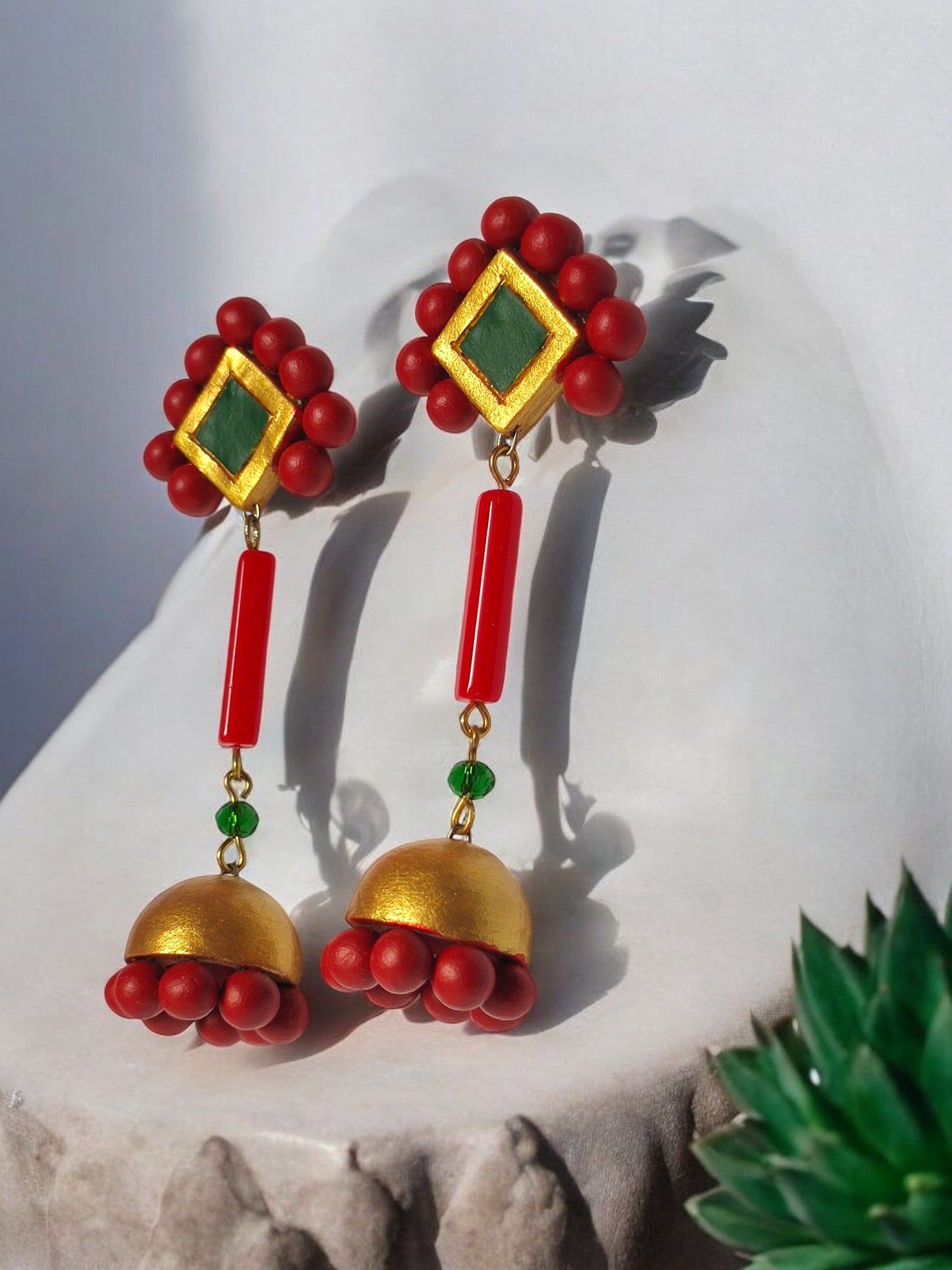 Experience exquisite adornment with our Abha Long Terracotta Jhumka. Each piece boasts elaborate patterns in a vibrant red, green, and gold color scheme, exuding a sense of opulence and exclusivity. Enhance your fashion with this essential statement accessory.